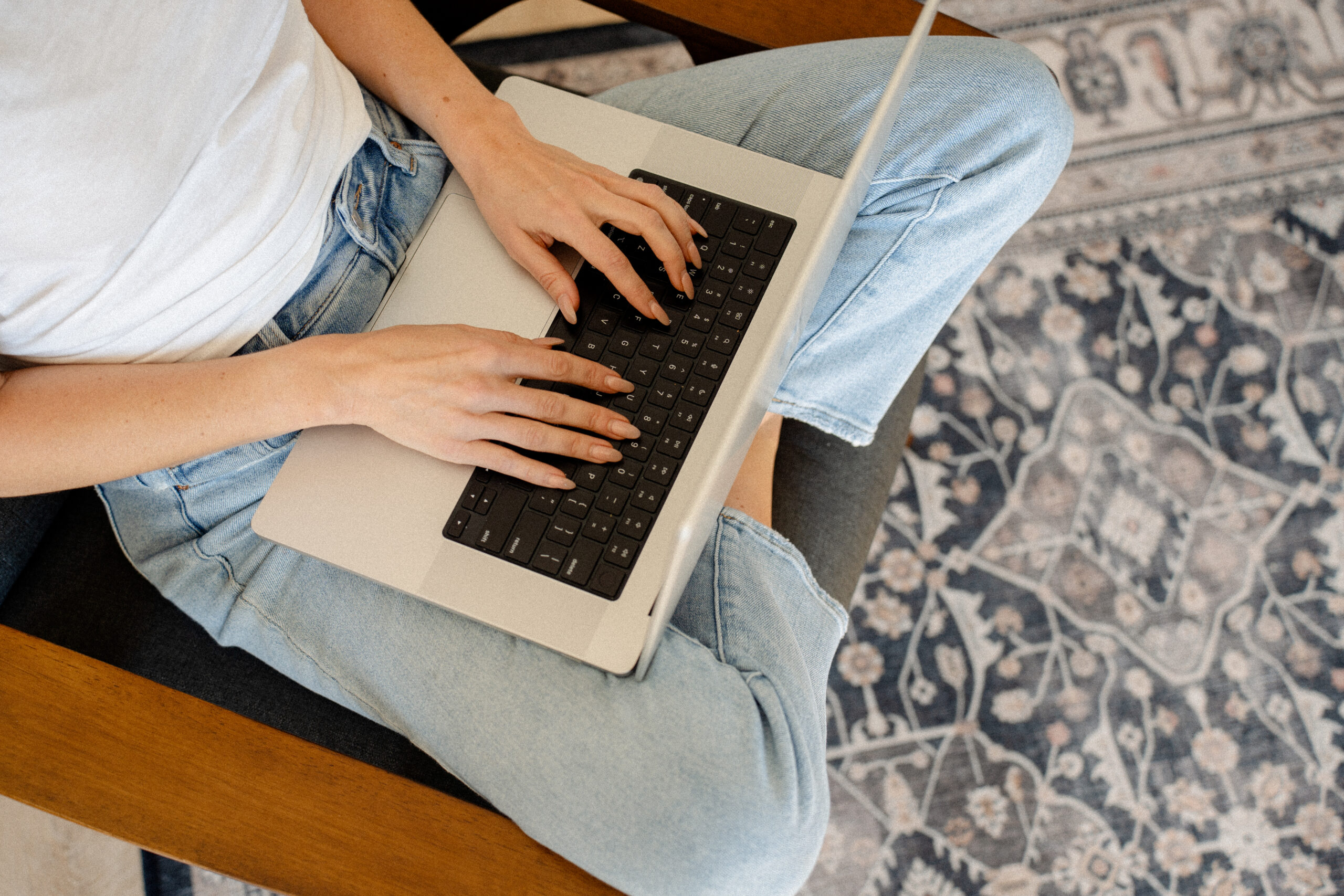 Woman smiling at laptop with coffee, grounded in alignment and ease in her business
